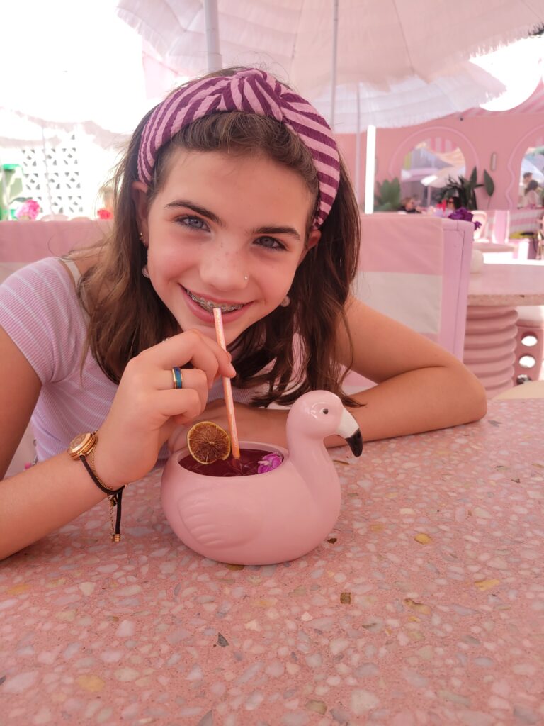 picture of Amelie, the owner of The Duckstore.nl drinking from a flamingo drink, full picture in pink hues.
