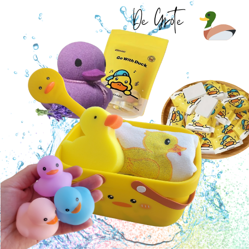 afbeelding van producten met rechtsboven in de tekst 'de grote' en dan een icon van een eend ernaast. afbeelding van een geel eend wasmandje, een eenden spons, een eenden borstel, een eenden handdoekje, een hand met 3 rubberen eendjes in de kleuren pastel blauw, roze en paars , een paarse eenden bad bruisbal, een zakje met 20 instant gezichtsdoekjes van Go Duck en een mandje met de instant gezichtdoek tabletjes in gele Go Duck verpakking. Op de achtergrond is een water splash zichtbaar en regenboog glitter.